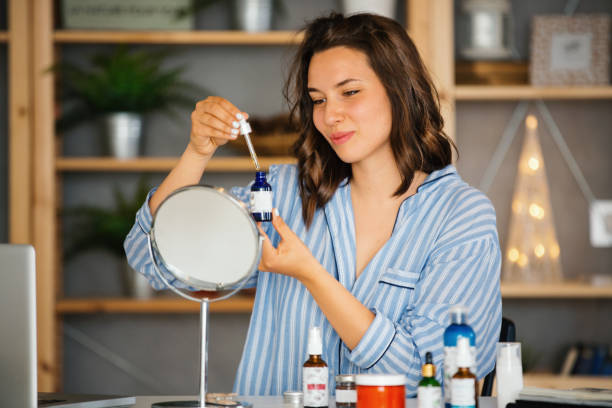 Woman applying retinol serum in front of a mirror, demonstrating skincare routine.