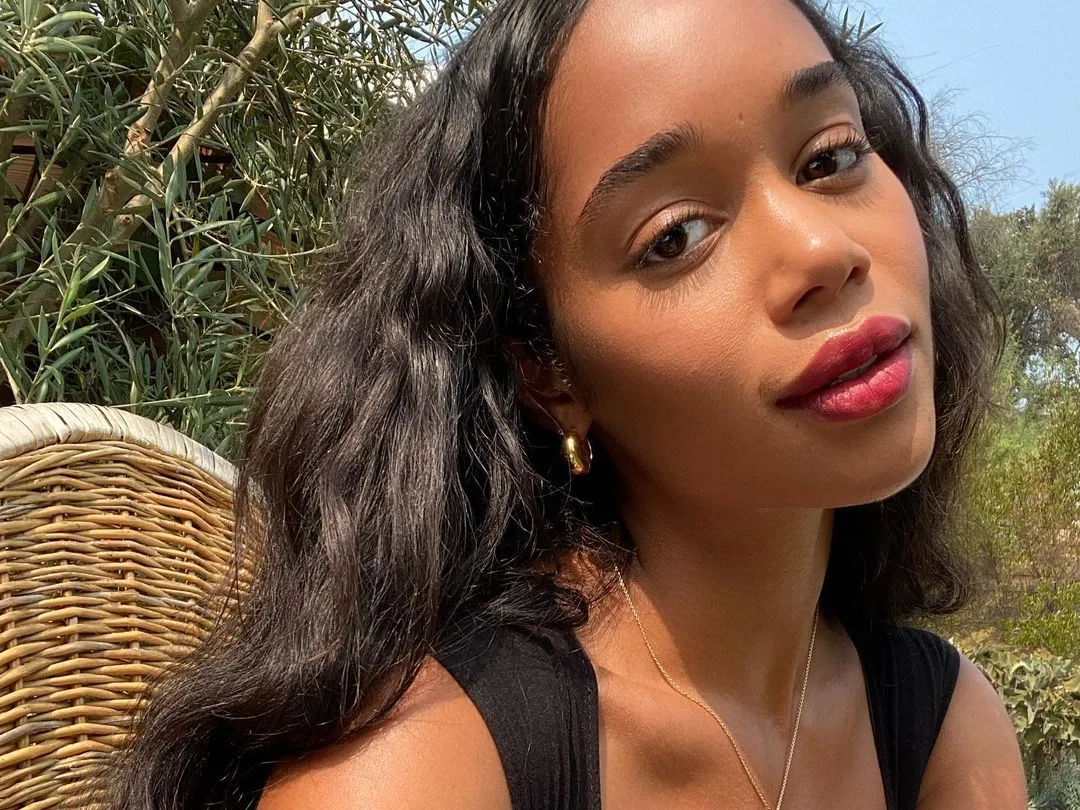 A woman with a dewy, soft complexion, embodying the 'Cloud Skin' trend, in an outdoor setting.