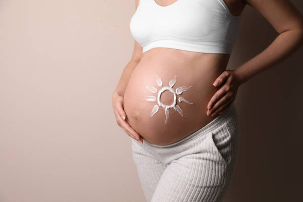 Pregnant woman with sun-shaped skincare cream on her belly, illustrating safe skincare for pregnancy.